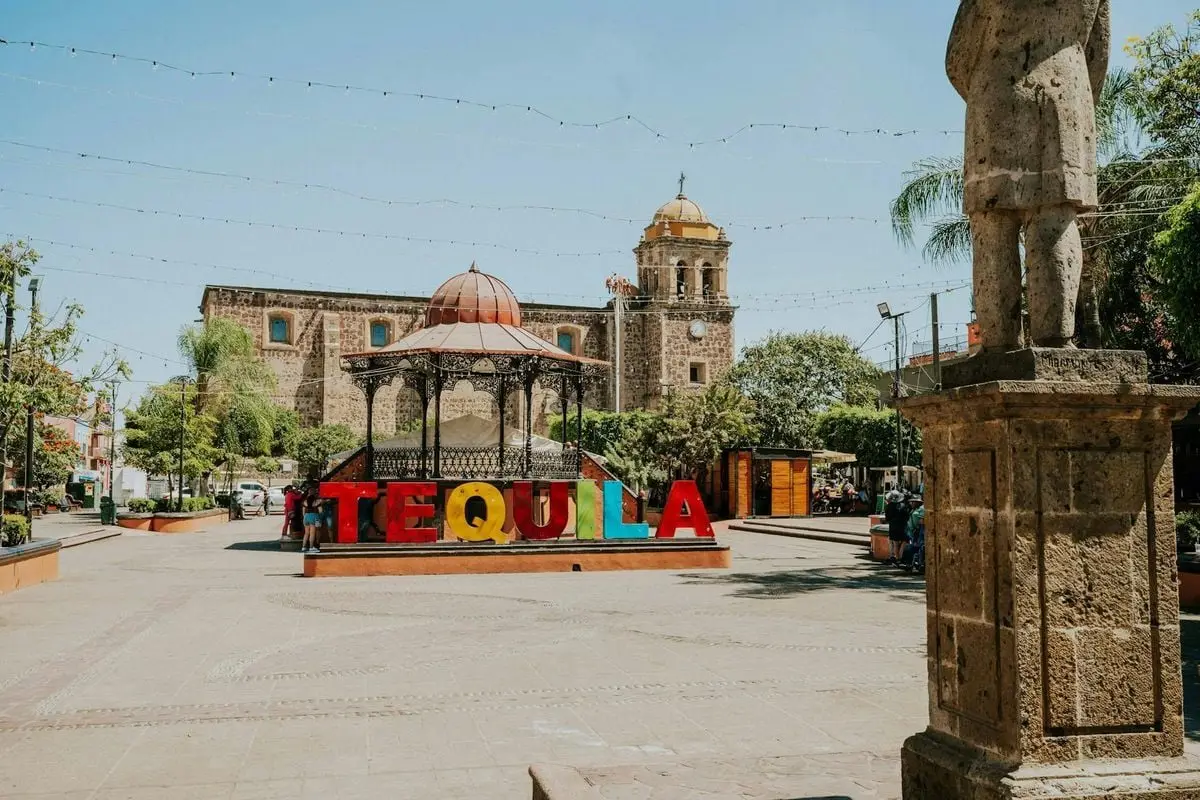 Vibrant Tequila sign in sunny Mexican plaza with historic architecture.
