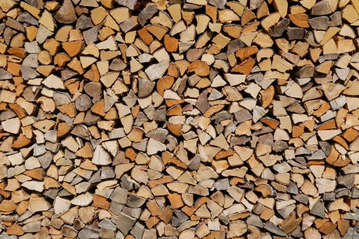 Detailed image of a neatly stacked pile of chopped firewood in warm tones.
