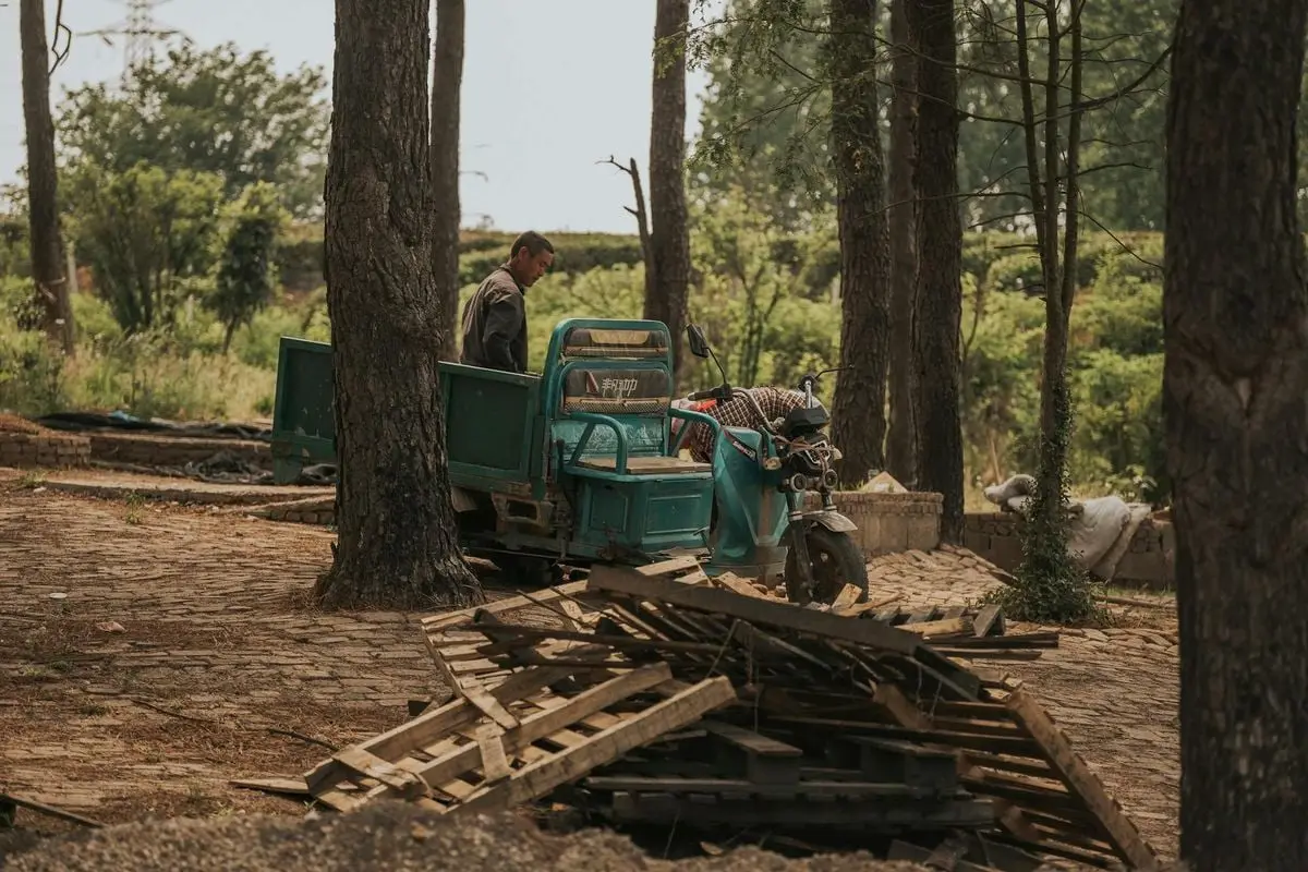 A man operates a motorized vehicle in a serene forest setting surrounded by trees and wood planks.