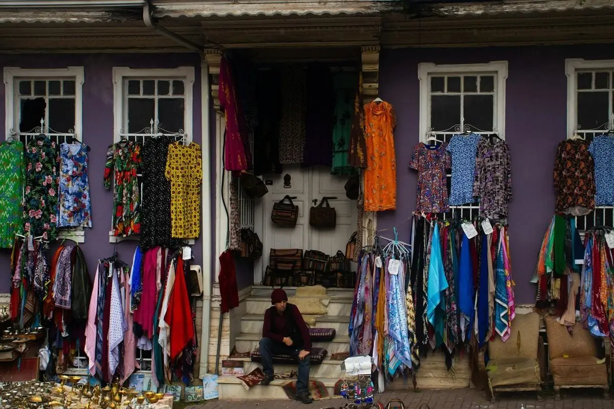 Outdoor market stall with vibrant fabrics and clothing in Istanbul's lively market.