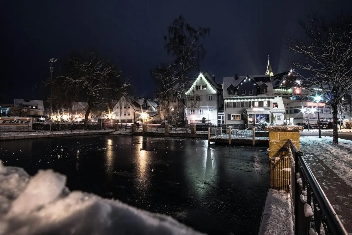 Captivating night cityscape in Welzheim, Germany, with illuminated buildings and snow-covered surroundings.