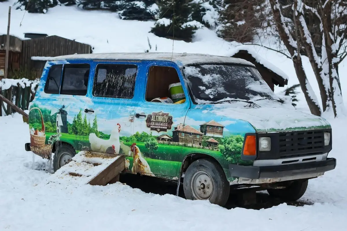 Abandoned van with a colorful mural covered in snow, set in a winter landscape in Türkiye.