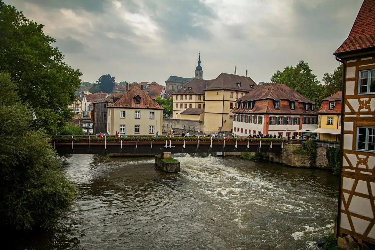 Cozy riverside view of historic buildings and bridge in Bayreuth, Germany.