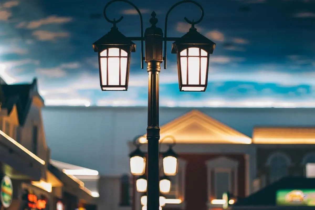 A tranquil street scene with illuminated lamps and architectural backdrop at twilight.