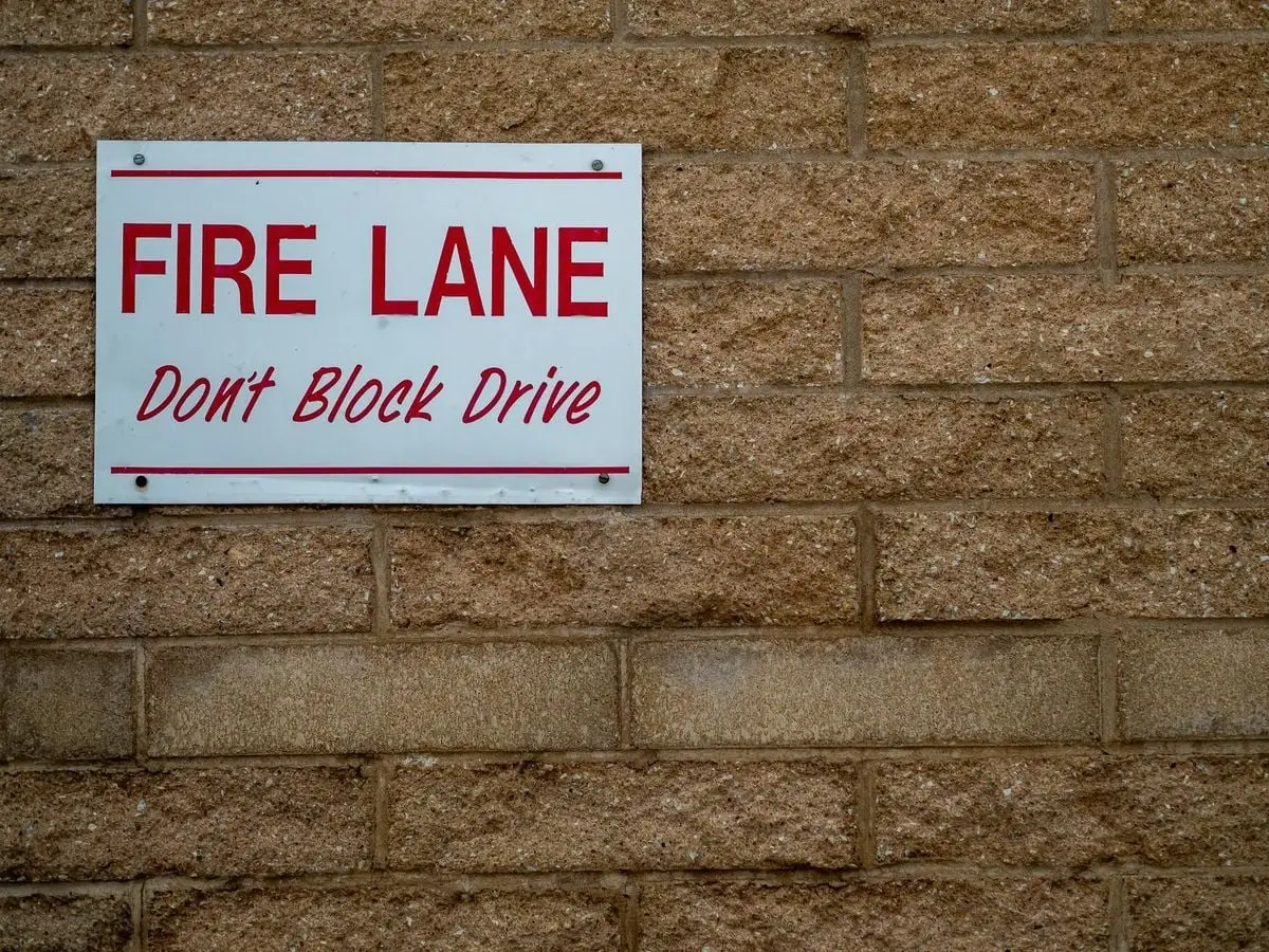 Close-up of a 'Fire Lane' warning sign on a textured brick wall.
