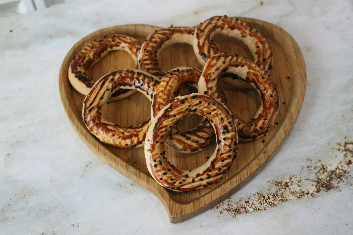 Freshly baked Turkish simit on a heart-shaped wooden platter.