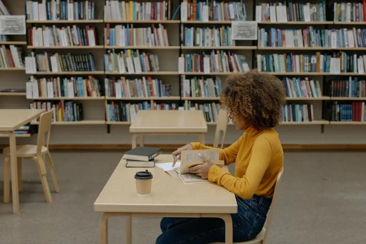 A focused woman reading in a library, highlighting education and learning.