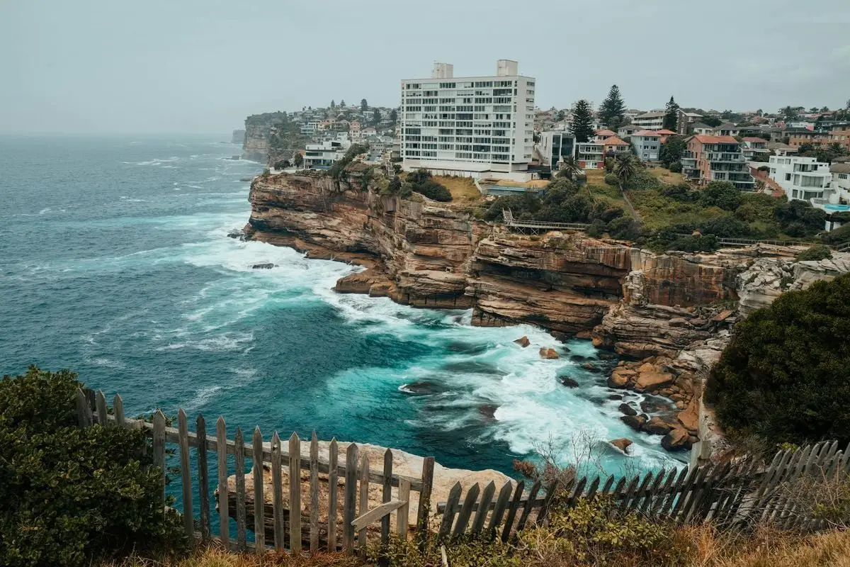 Breathtaking view of Sydney's rocky coastline with ocean waves and cityscape backdrop.