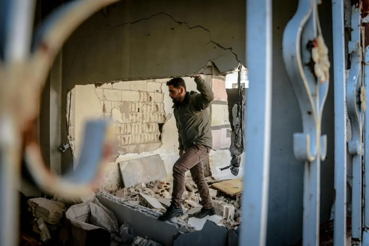 A man navigates through a damaged building in Idlib, Syria, symbolizing resilience amidst destruction.