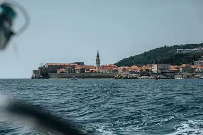 Stunning coastal shot of Budva's old town with its iconic red roofs and church against the Adriatic Sea.