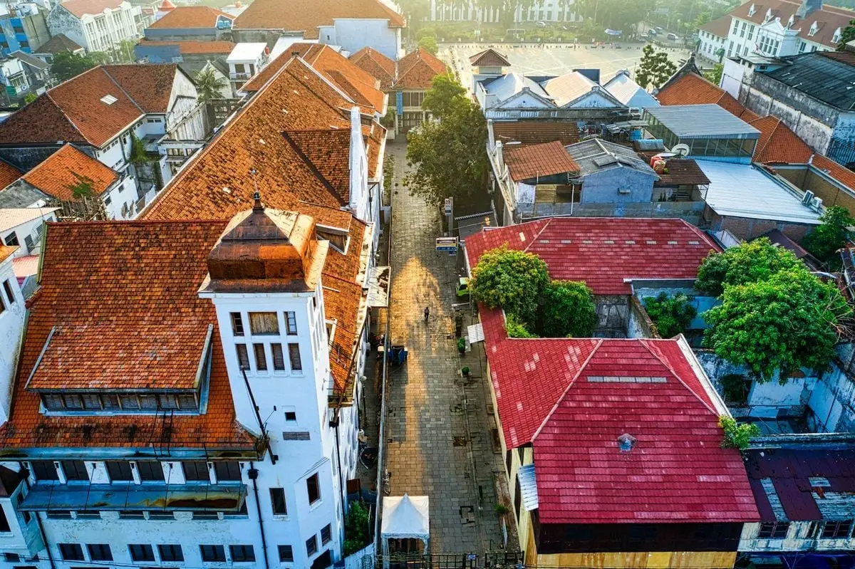 Aerial shot of Jakarta's historic buildings with red-tiled roofs at sunrise, showcasing traditional architecture.