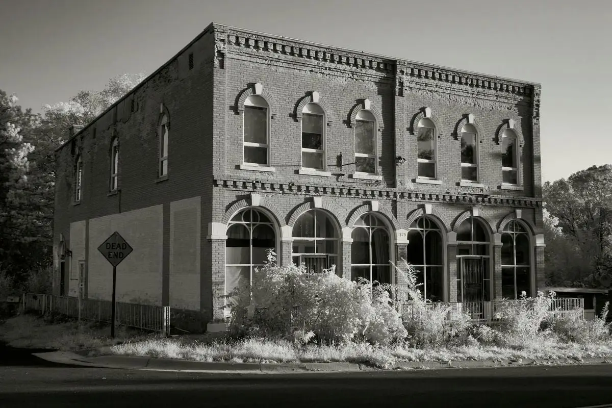 Black and white photo of a historic building in Weaver, MN with a dead-end sign.
