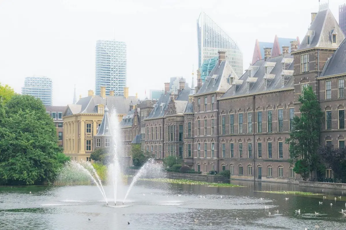 The Binnenhof in The Hague with a fountain and urban skyline backdrop.