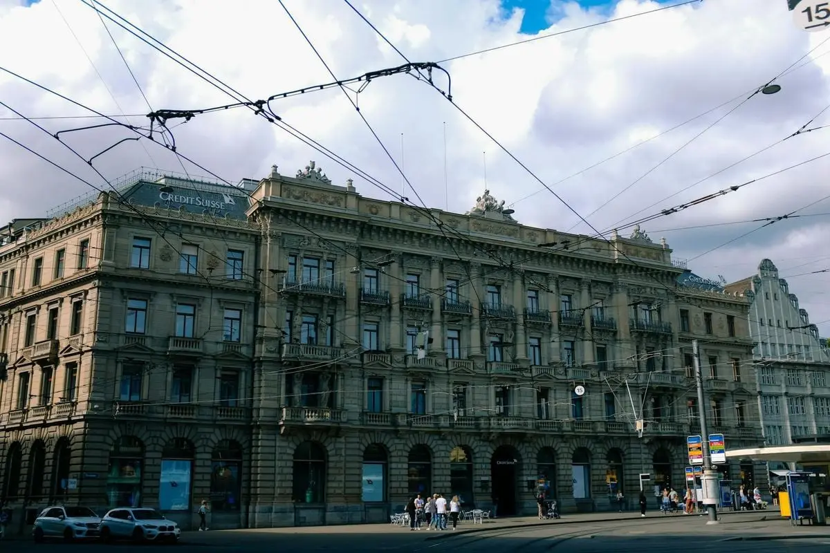 An ornate historic building in a city center with visible tram lines and street activity.