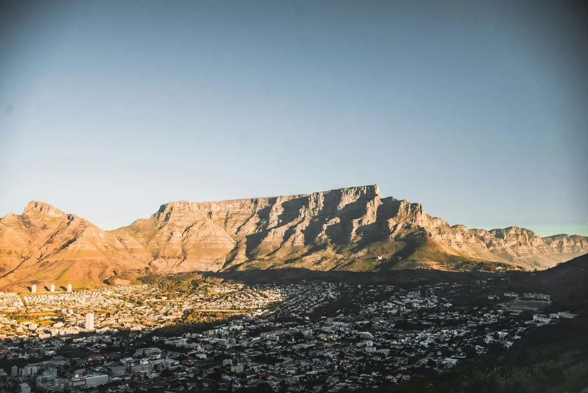 A breathtaking view of Cape Town's cityscape with the iconic Table Mountain in the backdrop during sunset.