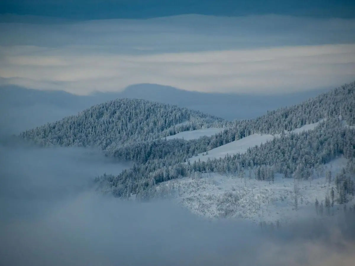 A breathtaking view of snow-covered mountains with clouds in a serene winter landscape.