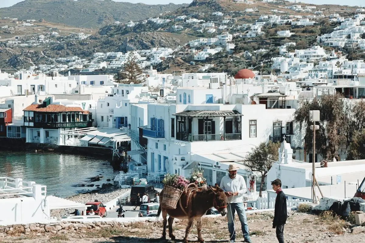 Beautiful view of Mykonos town with locals and a donkey under the clear sky.