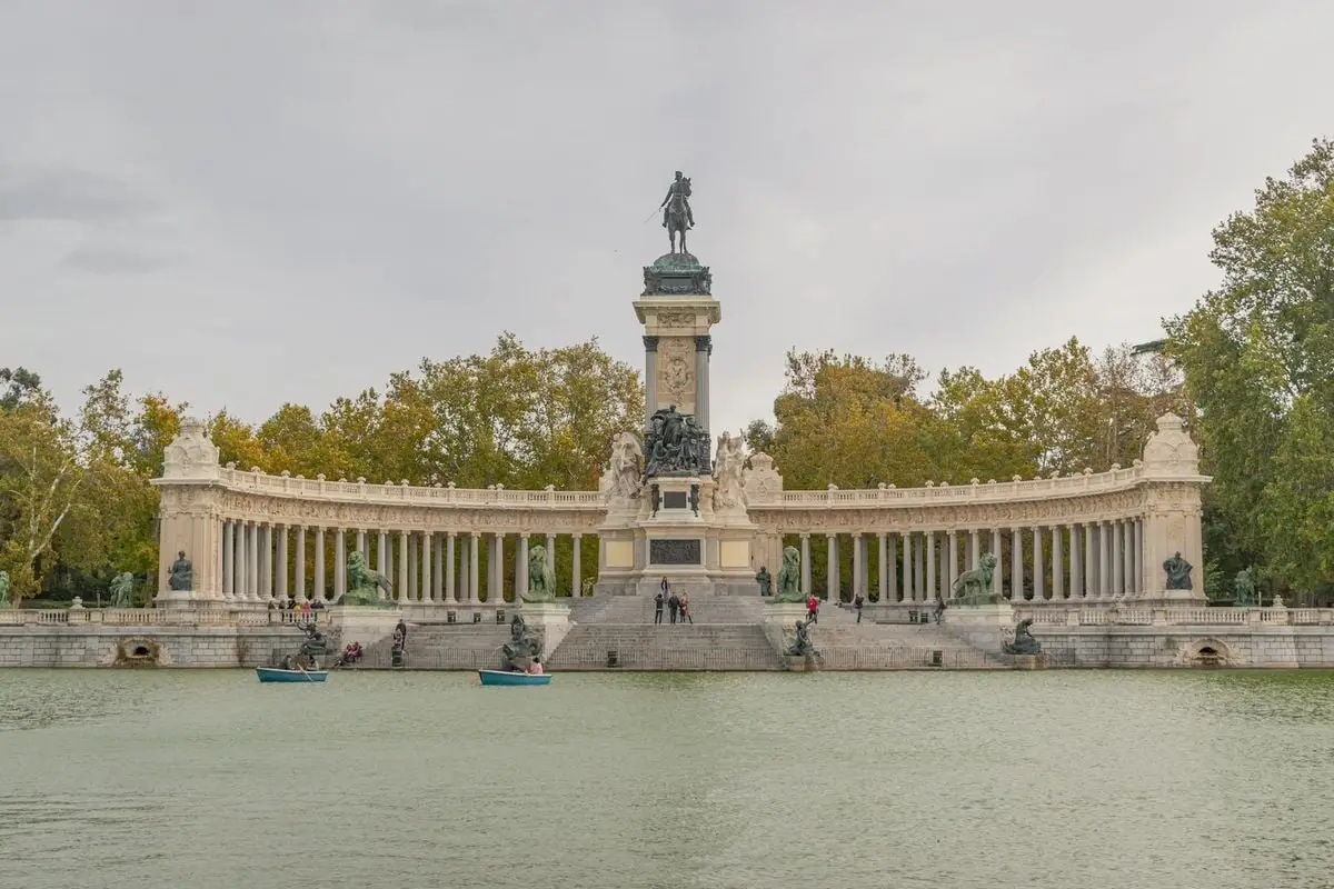 The majestic Monument to Alfonso XII at El Retiro Park, Madrid, with a serene lake view.