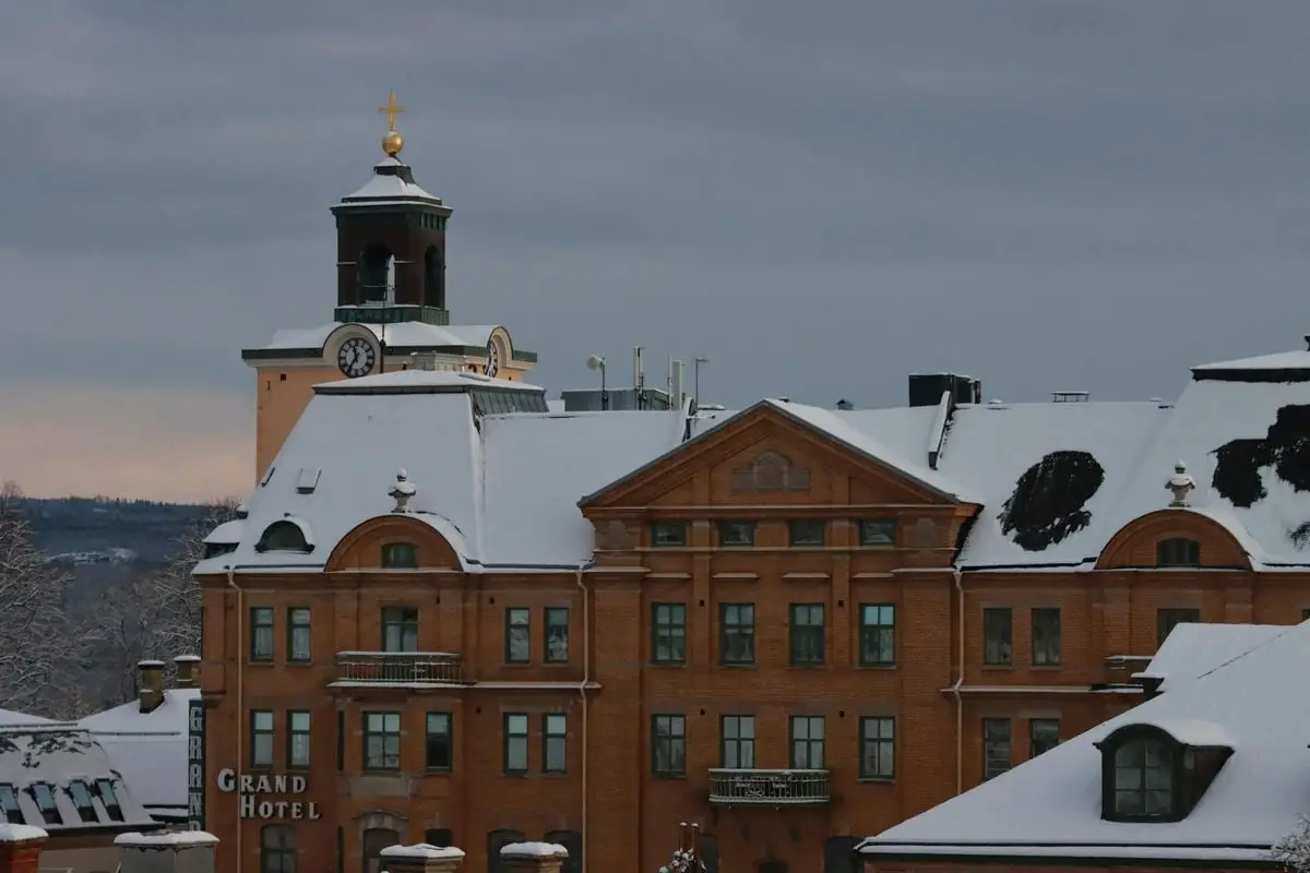 A stunning view of the snow-covered Grand Hotel building with a clock tower in winter.