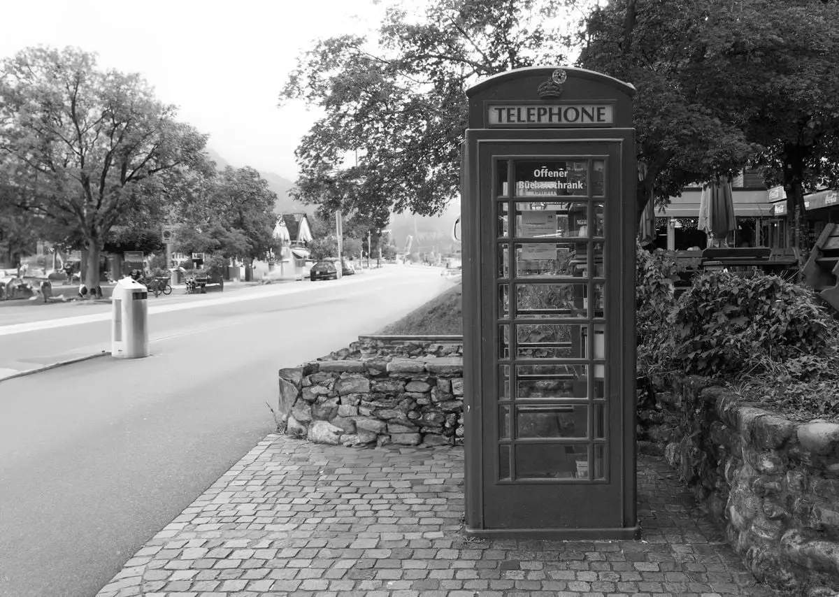 A vintage telephone booth on a city street in Interlaken, Switzerland, showcasing urban charm.