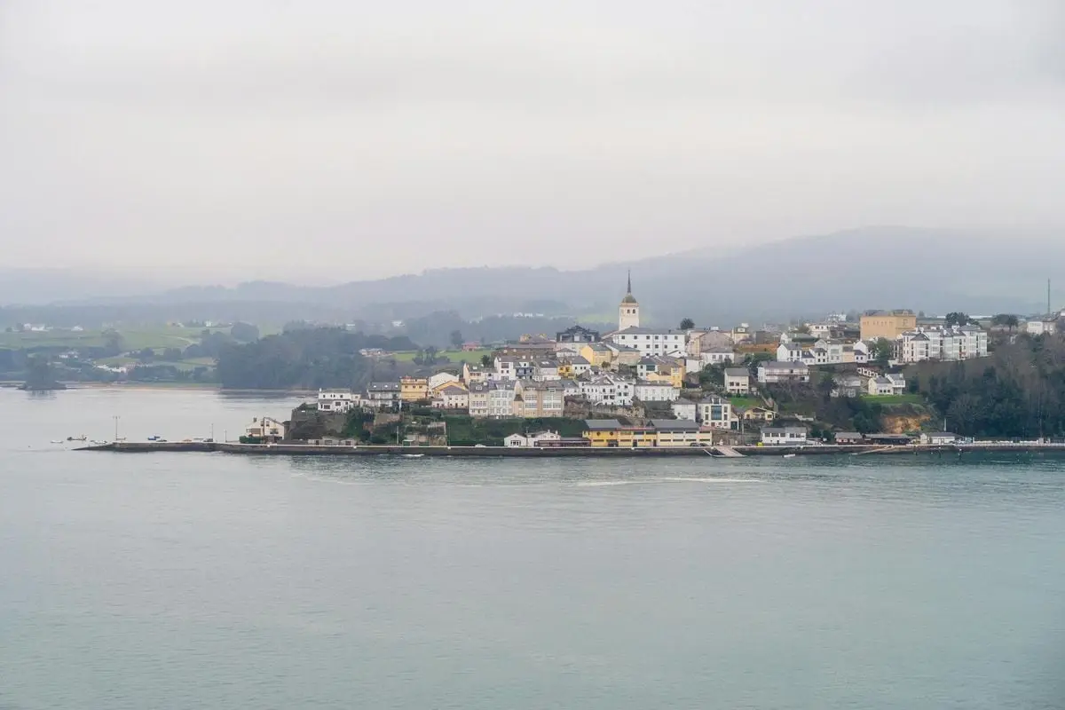 Picturesque view of a coastal town with a prominent church steeple on a foggy day.
