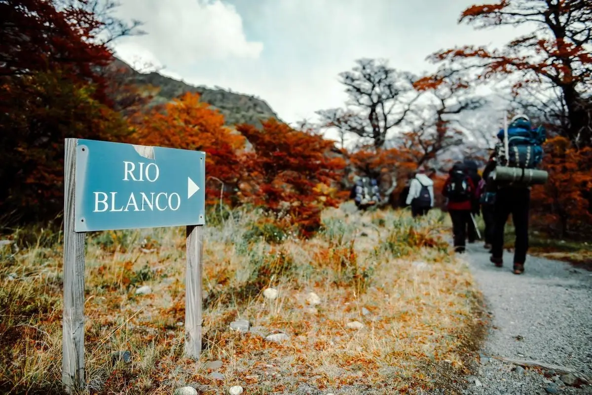 Backpackers on an autumn hike to Rio Blanco in El Chalten, Argentina with vibrant fall colors.