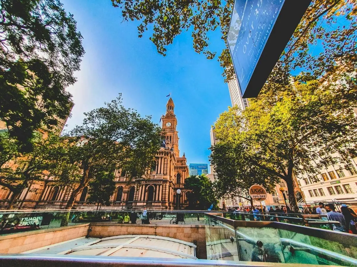 A vibrant view of Sydney's iconic clock tower surrounded by lush greenery and urban architecture.