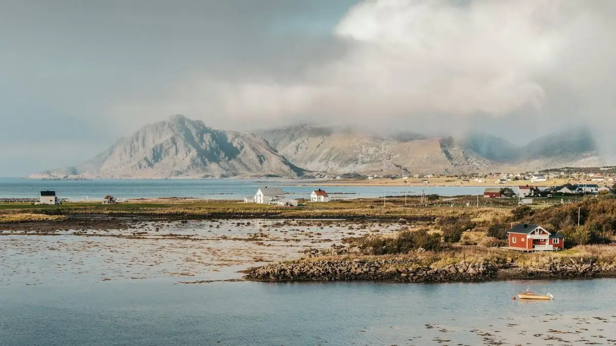 Scenic view of Lofoten Islands with mountains, sea, and cozy houses under cloudy skies.