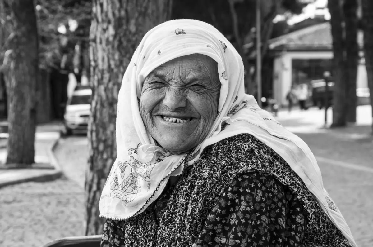 Portrait of a smiling elderly woman outdoors in Birgi village, Türkiye.