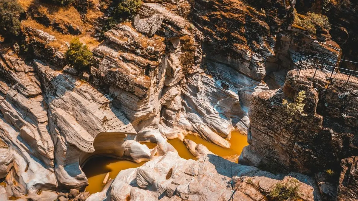 Stunning aerial view of a rocky canyon with flowing water in Uşak, Türkiye, during a sunny day.
