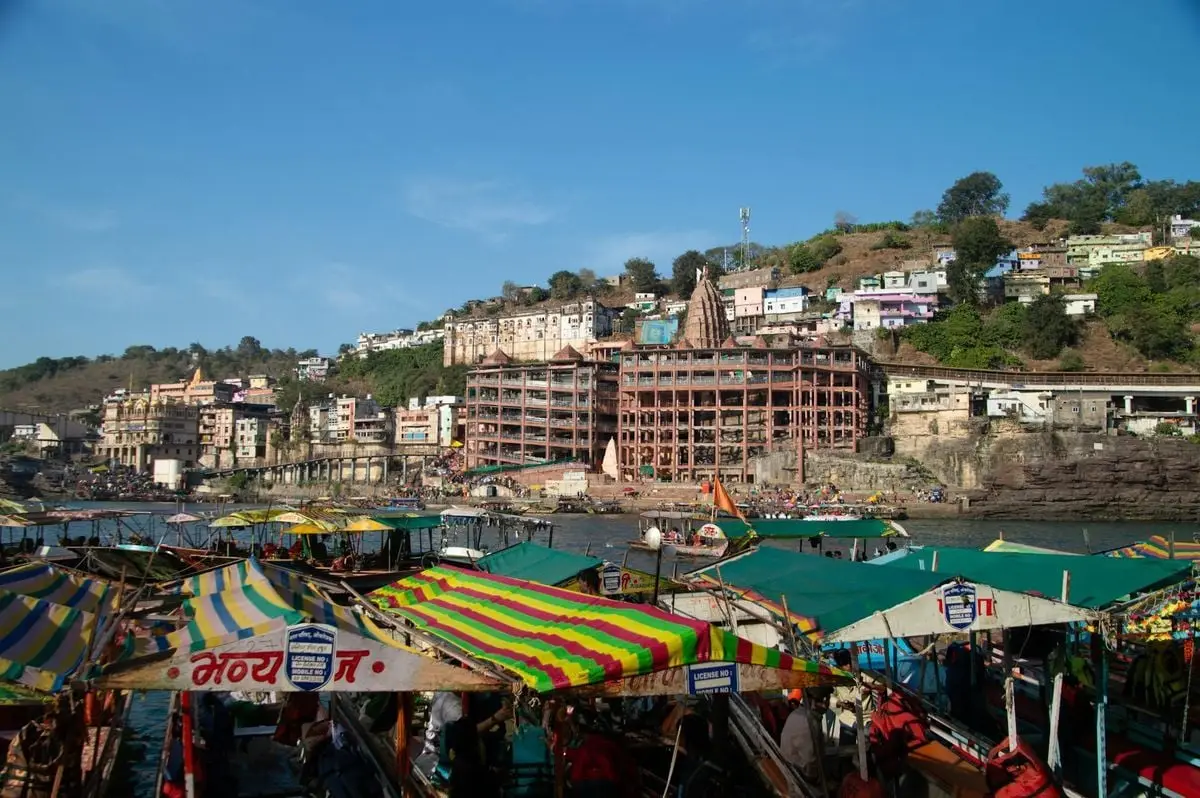 Vibrant view of Maheshwar town with colorful boats on the Narmada River in India.