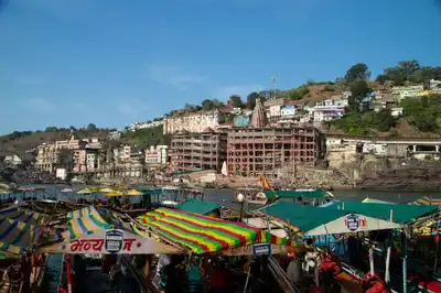 Vibrant view of Maheshwar town with colorful boats on the Narmada River in India.