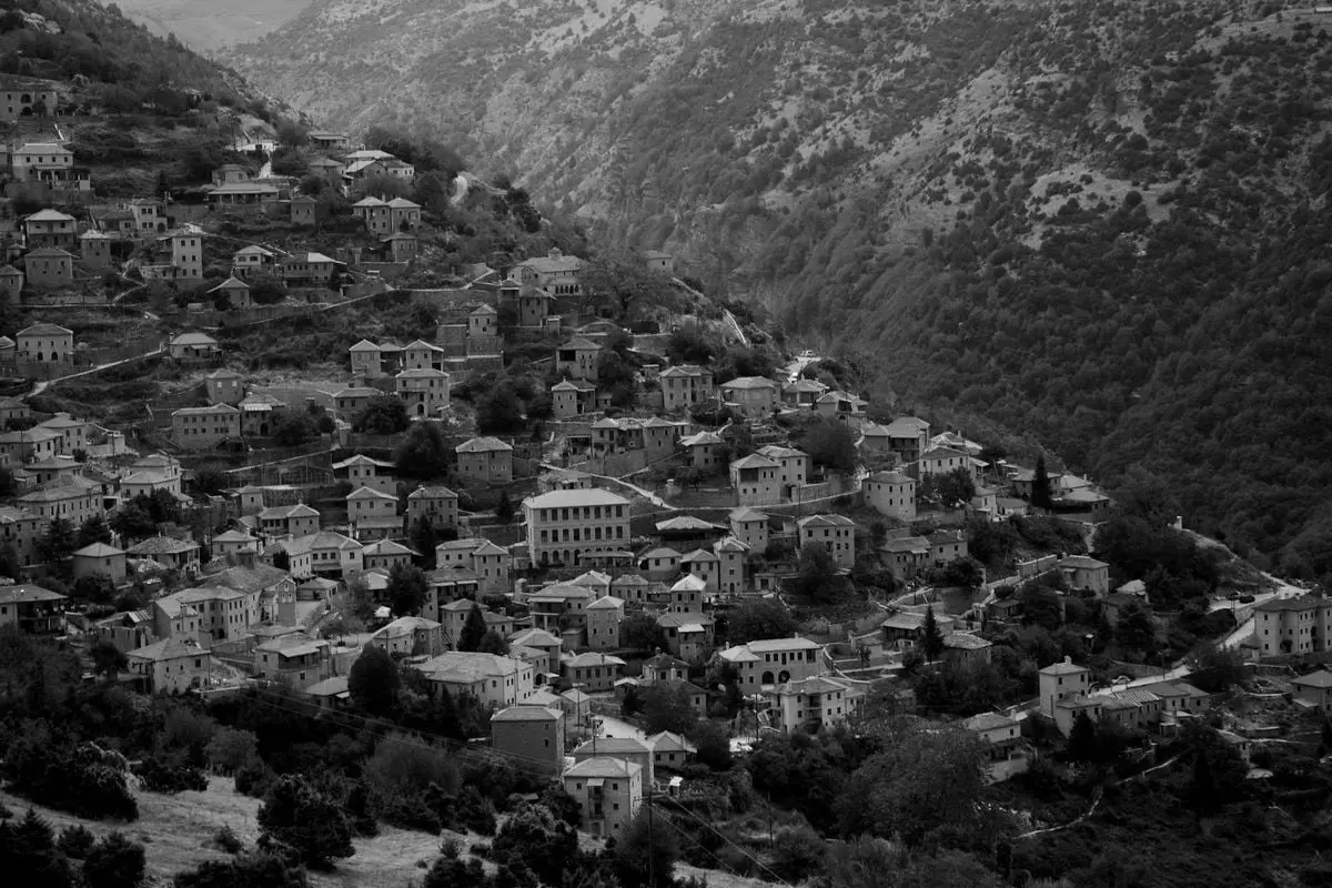 Aerial view of a mountain town with houses nestled on hills in black and white.