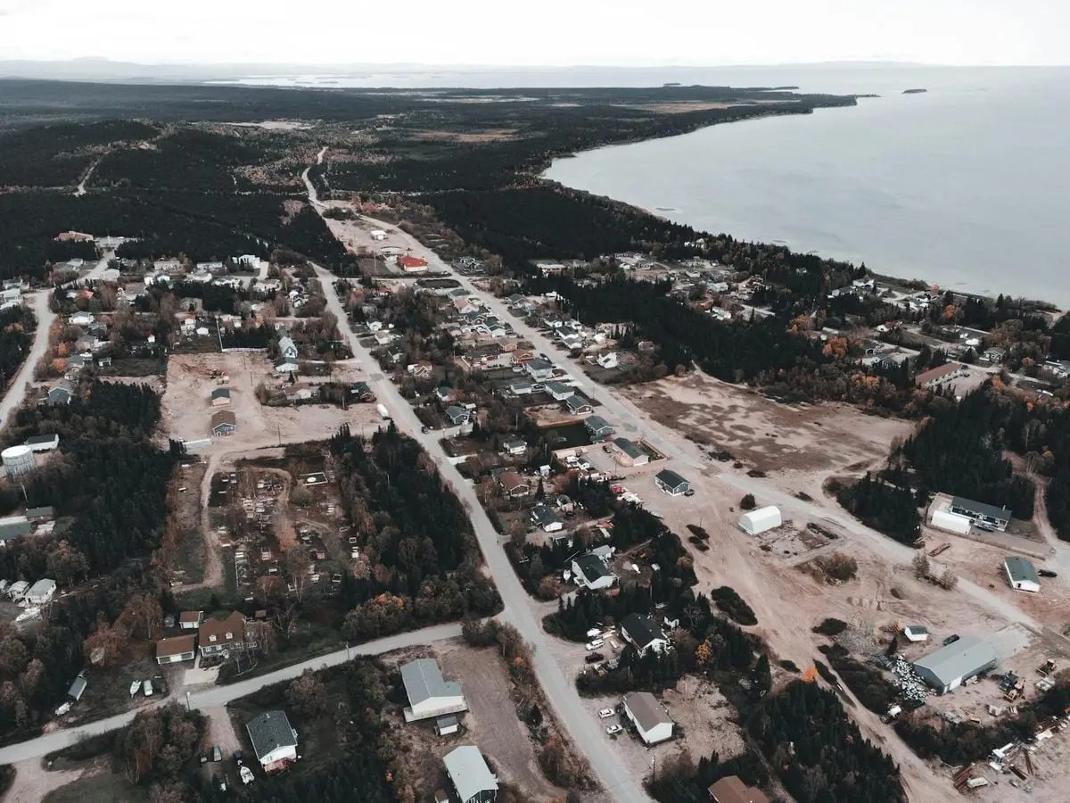 Drone capture of a scenic coastal town with forests meeting the seashore.