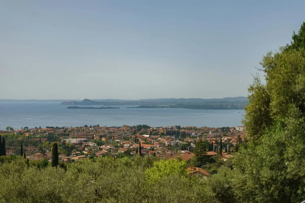 Panoramic view of Toscolano Maderno overlooking Lake Garda, highlighting lush greenery and a serene lakeside town.