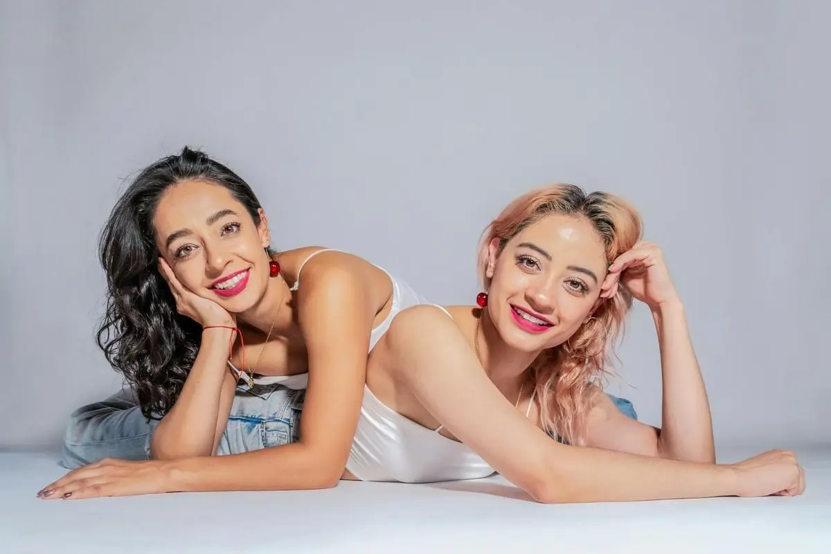 Two young women lying on the floor, showcasing friendship and joy with vibrant smiles in Ciudad de México.