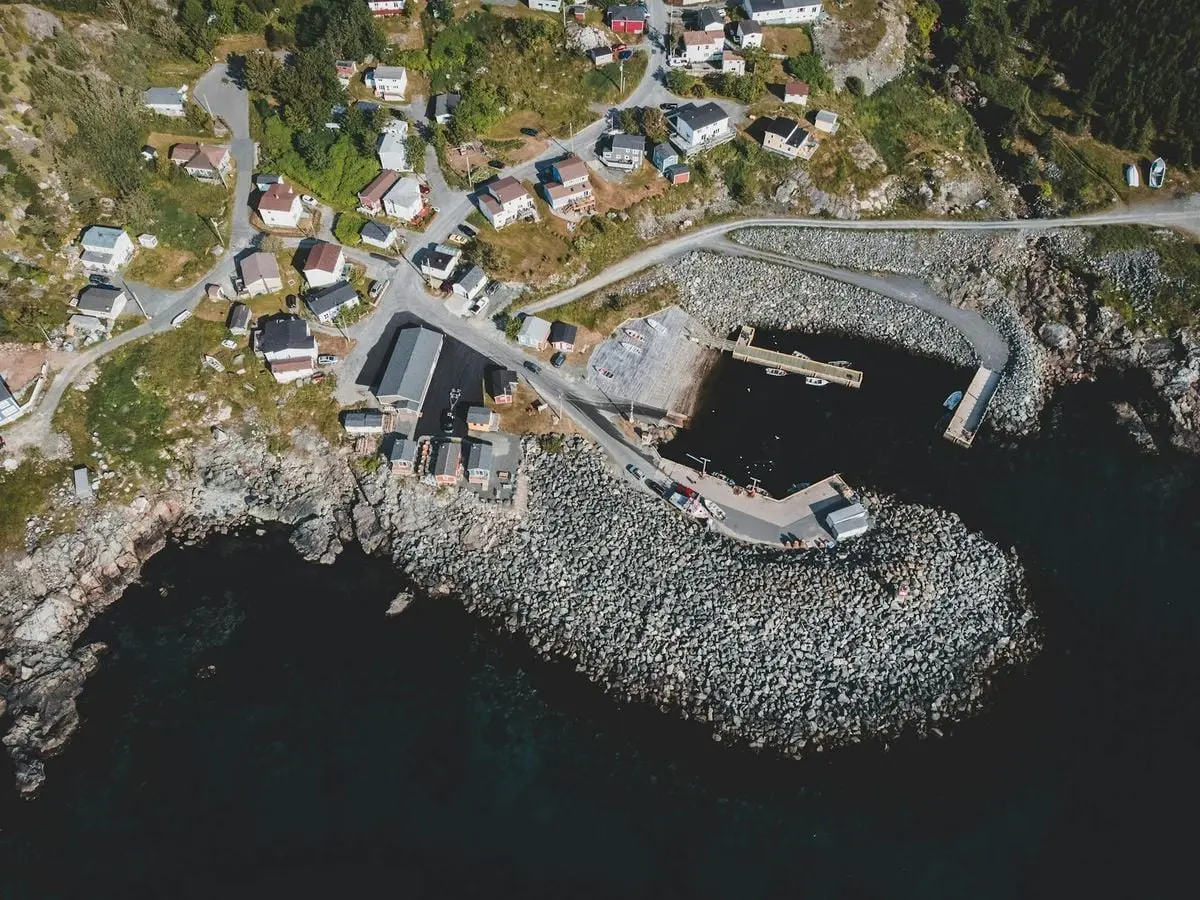 A high-angle aerial shot displaying a coastal village surrounded by rocky shores and lush greenery.