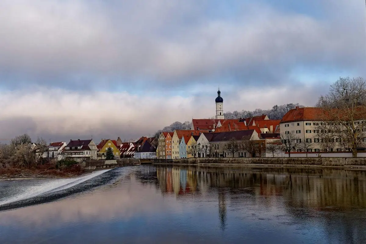 Charming winter view of Landsberg am Lech, Bavaria with architectural reflections in the river.