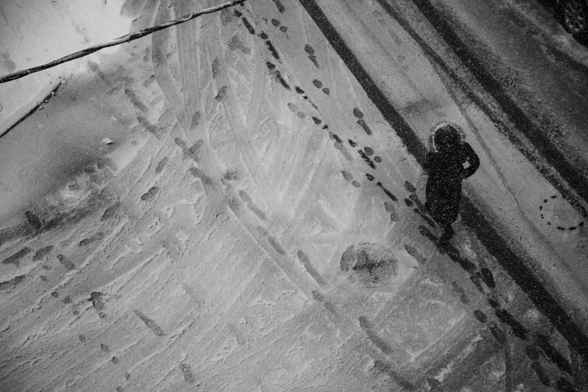 Black and white aerial photo of a person walking on a snow-covered street in Istanbul.