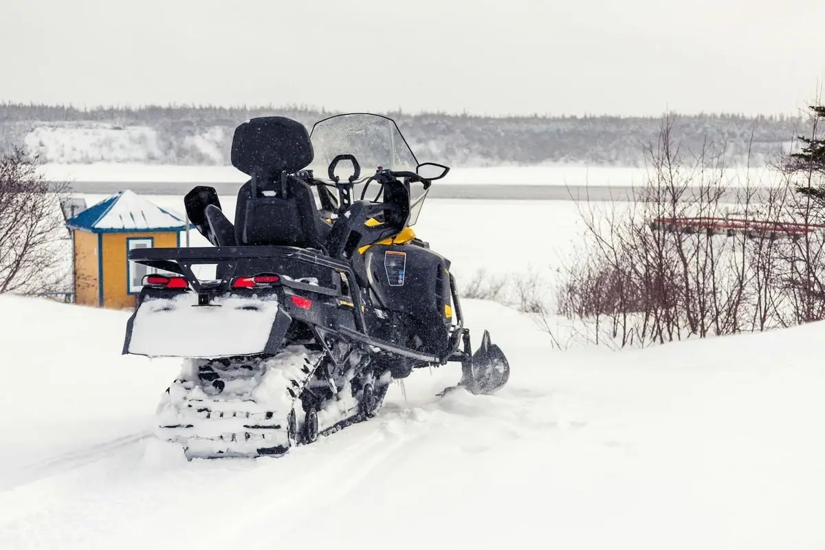 Snow-covered landscape in Chevery, Québec featuring a snowmobile on a snowy day.