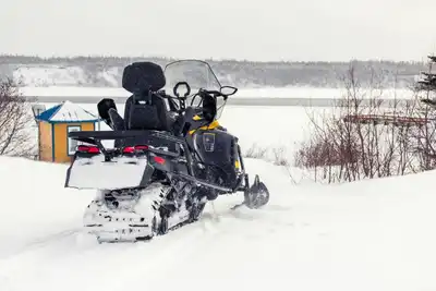 Snow-covered landscape in Chevery, Québec featuring a snowmobile on a snowy day.