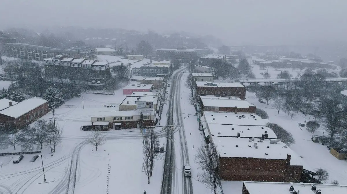 Aerial view of a snow-covered city street in winter, creating a serene urban scene.