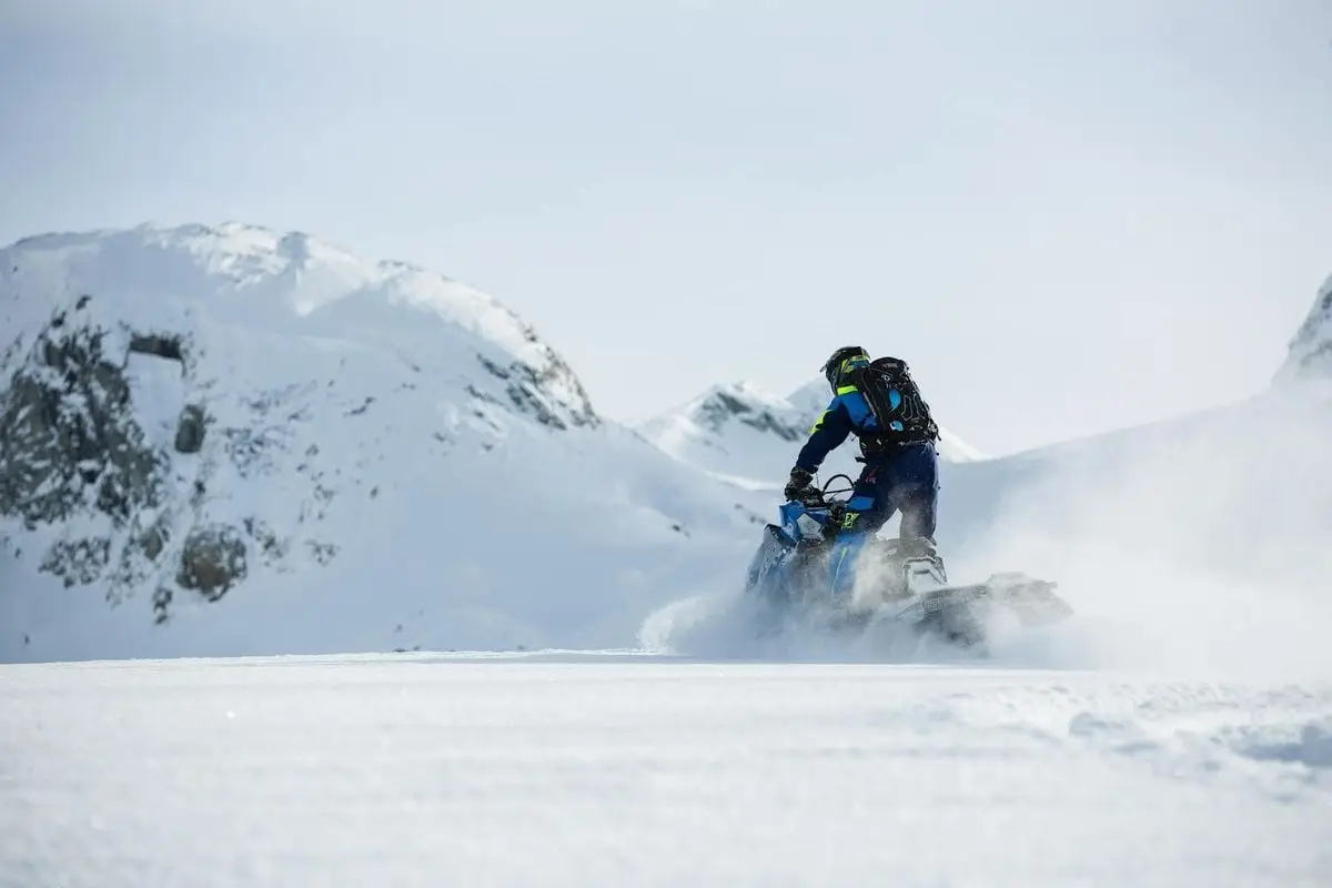 Exciting snowmobile ride across snow-covered mountains under clear winter skies.