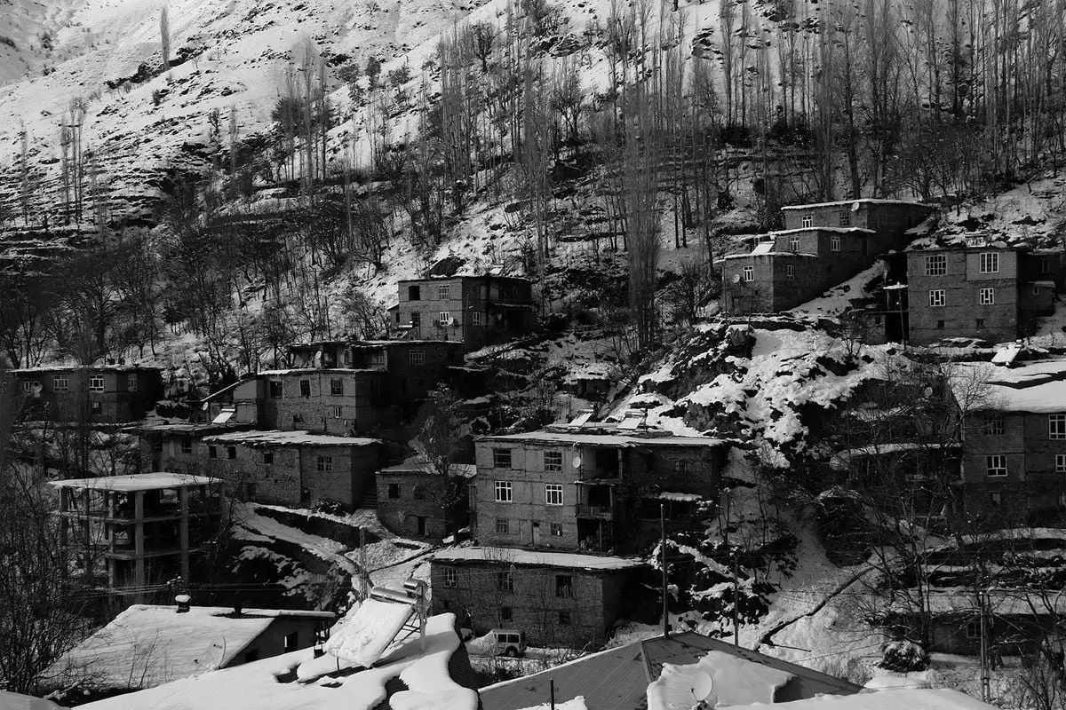 Charming snow-covered buildings on a hillside in Hizan, Bitlis, Türkiye, depict a serene winter scene.