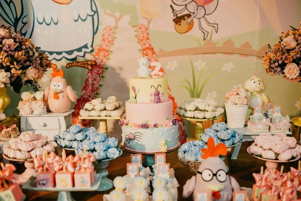 A whimsical dessert table setup at a children's birthday party featuring a colorful cake and cartoon decorations.
