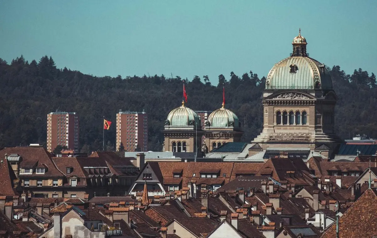 View of Berne's skyline with Swiss Parliament and historic rooftops under a clear sky.