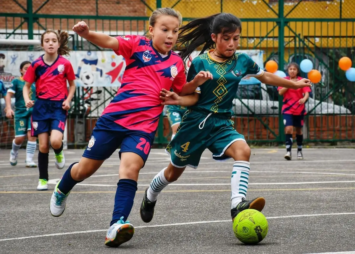Energetic game of young girls playing soccer on an outdoor field, showcasing teamwork and skill.