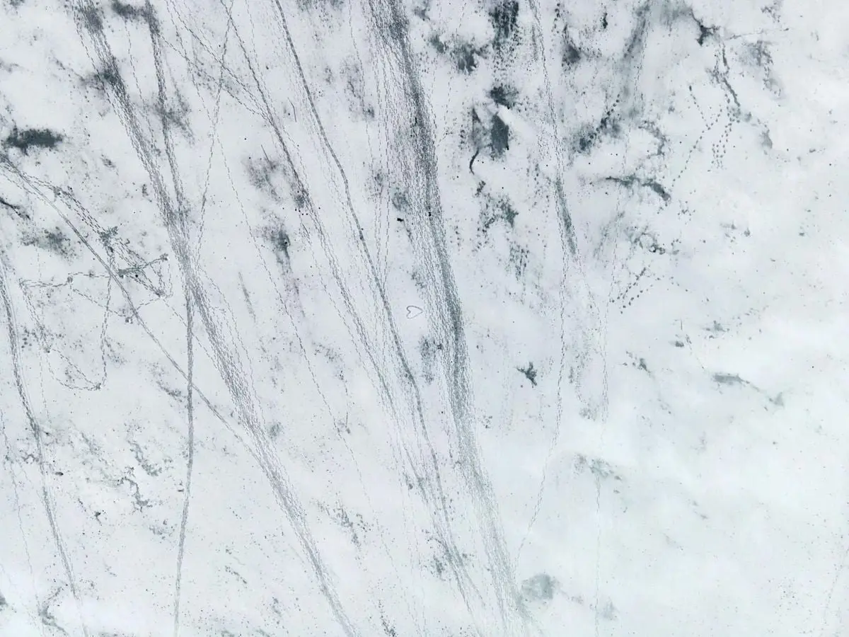 Aerial image showcasing a snow-covered terrain with visible tracks and patterns.