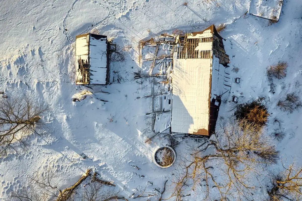 Aerial shot of a snow-covered, abandoned wooden barn in winter, MN, USA.