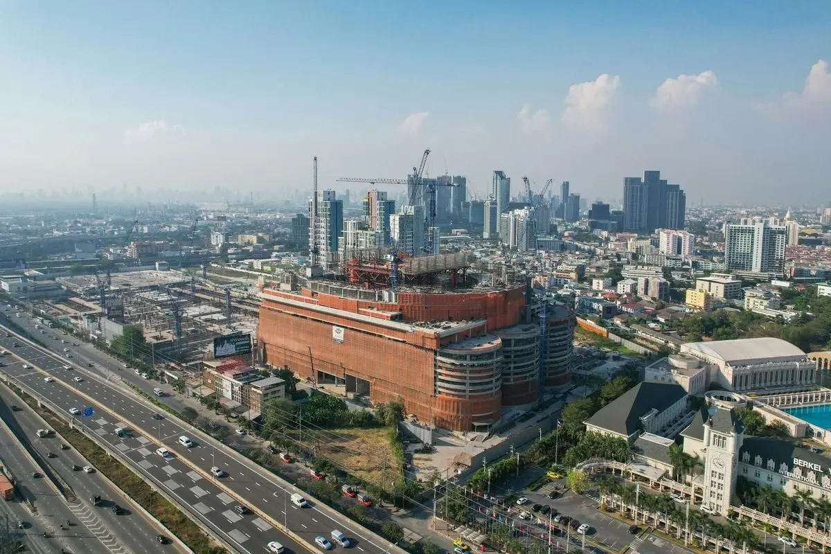 Aerial shot of an urban cityscape featuring a construction site amidst skyscrapers and a highway.